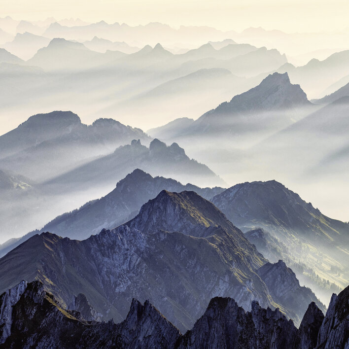 Berglandschaft mit sanften Hügeln und Nebel im Morgenlicht, die eine mystische Atmosphäre erzeugt.