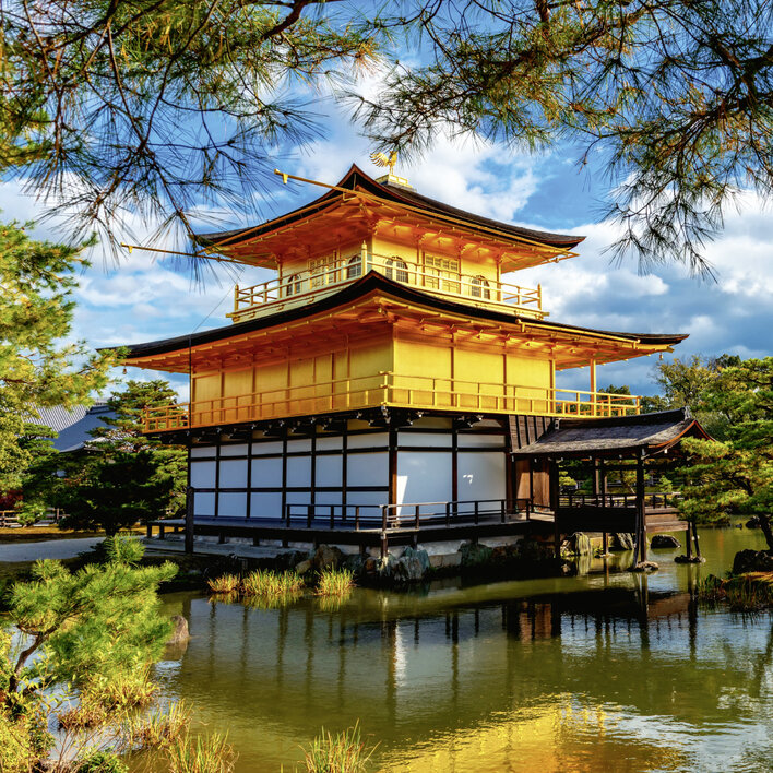 Goldener Pavillon in Kyoto, umgeben von einem malerischen Teich und üppiger Vegetation.