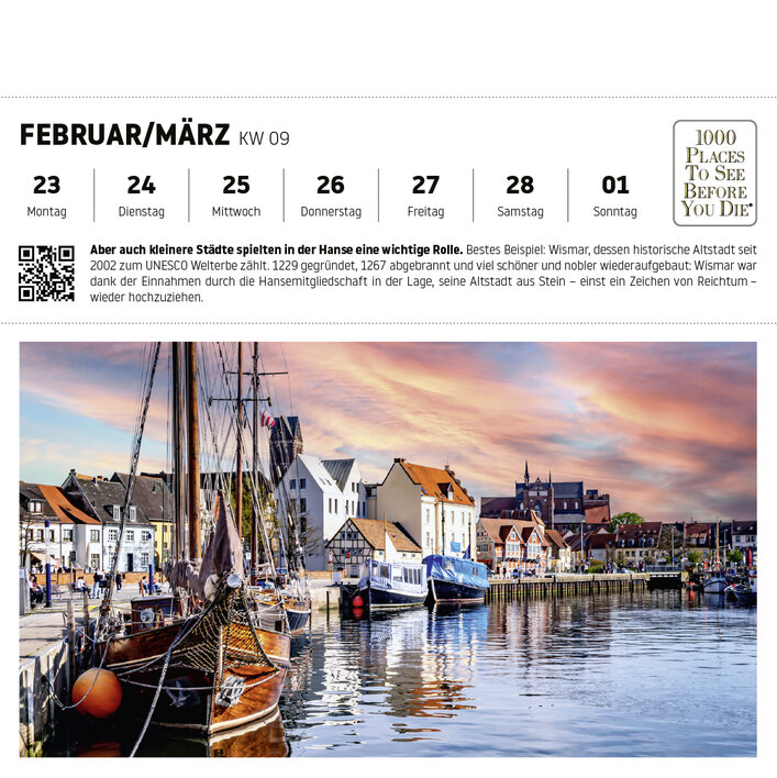 Blick auf den Hafen von Wismar mit historischen Gebäuden und Schiffen im Wasser, unter einem farbenfrohen Himmel.